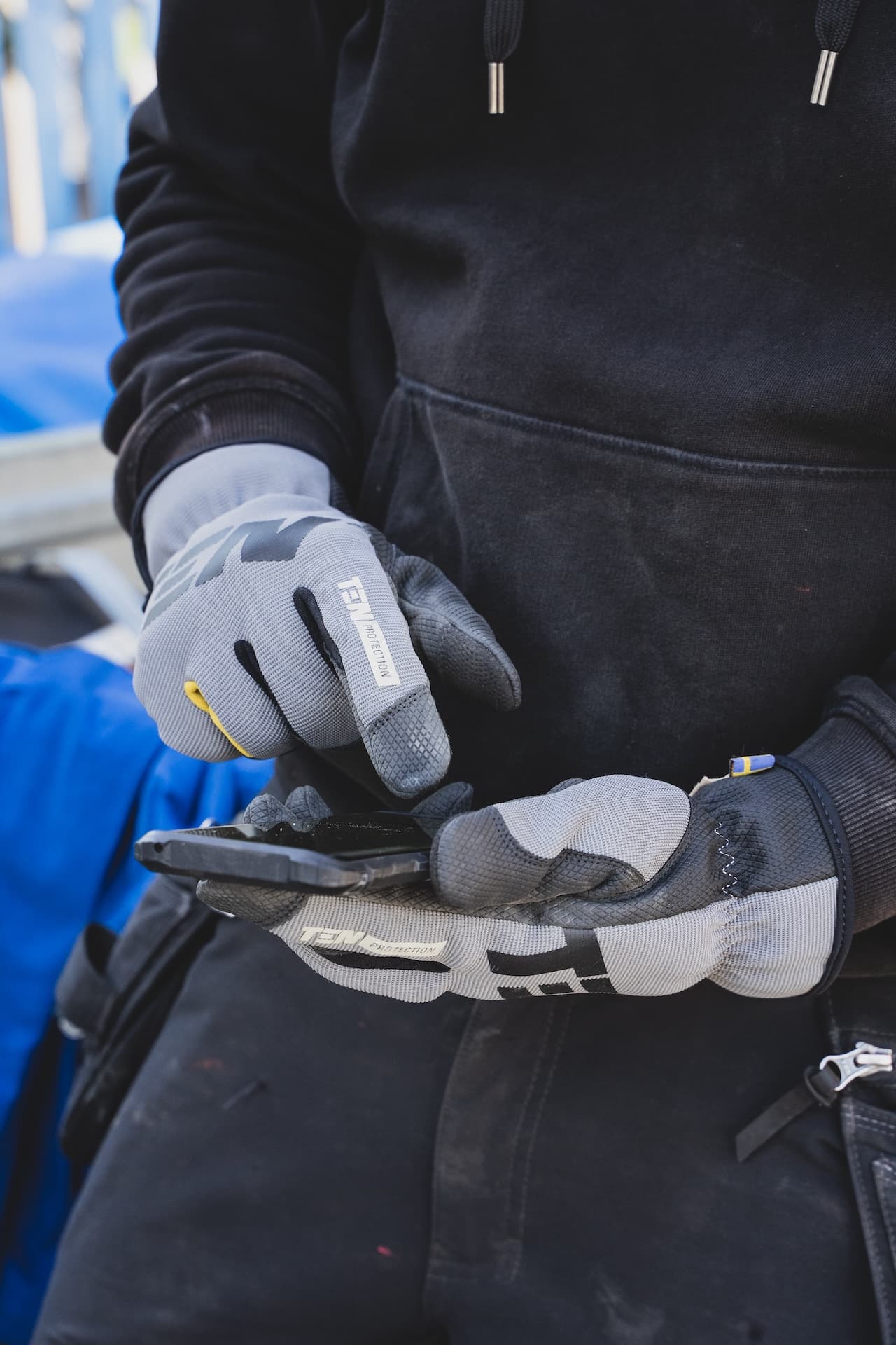 Bauarbeiter mit Handschuhen und Smartphone bereit für Ihre Anfrage